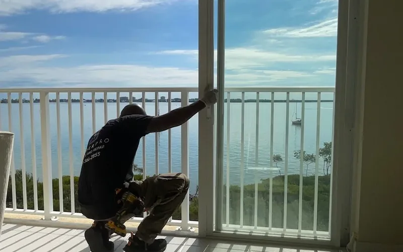 Technician servicing a sliding balcony door at a Florida condo building