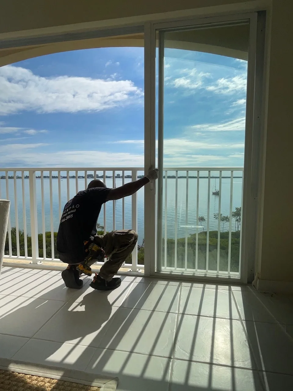 Technician servicing a sliding balcony door at a Florida condo building