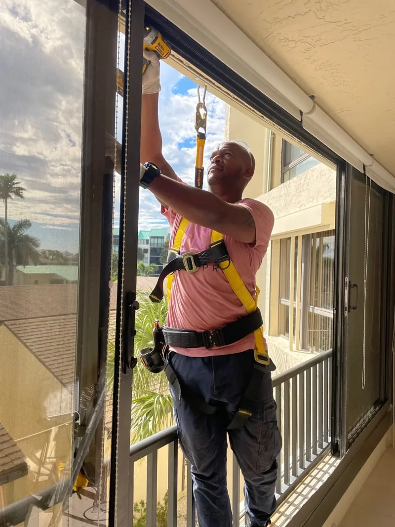 SliderPro technician in a safety harness servicing a condo balcony sliding door