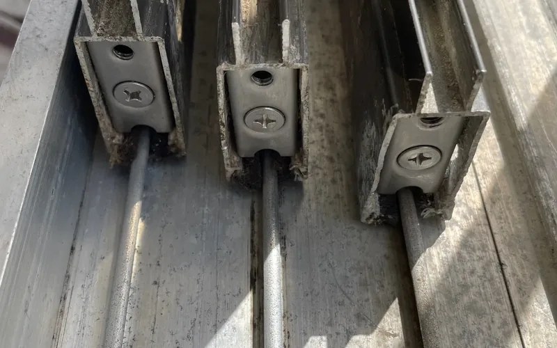 Close-up of worn sliding door rollers on their track rails