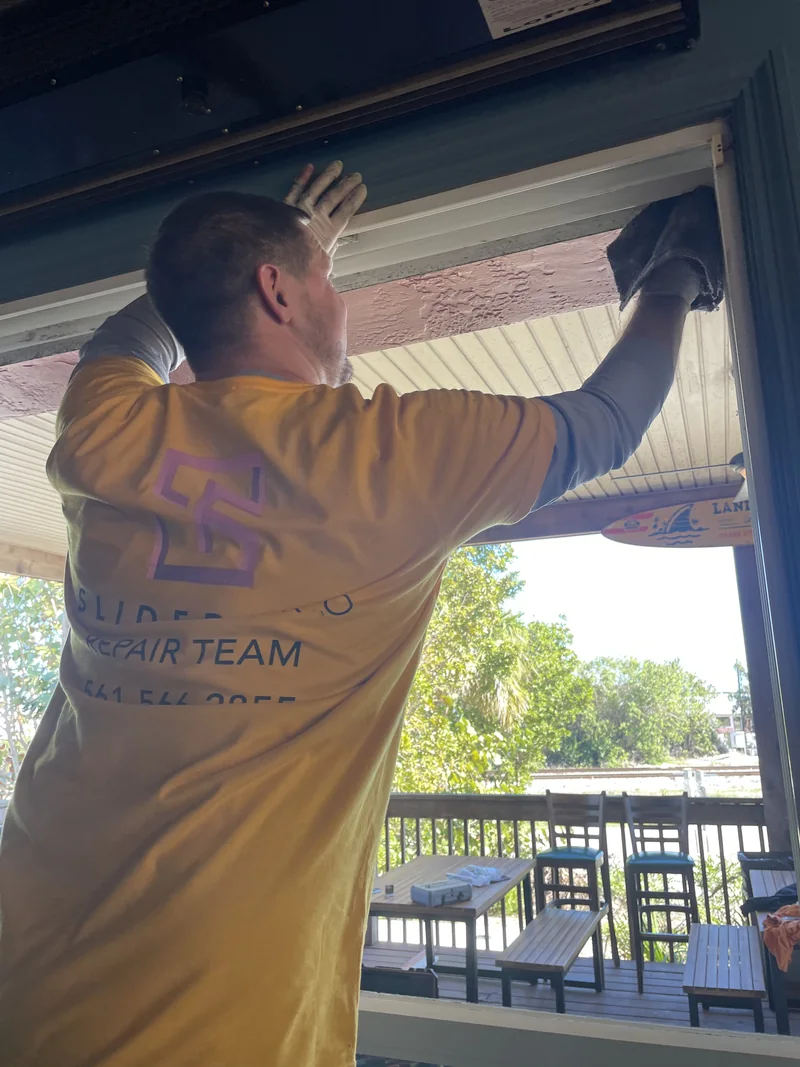 SliderPro technician cleaning the head track of a sliding door that opens onto a covered porch