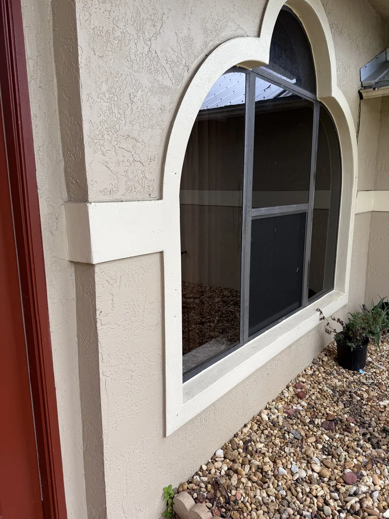 Arched window with a wide decorative stucco surround, showing the round-top profile that new glass has to match