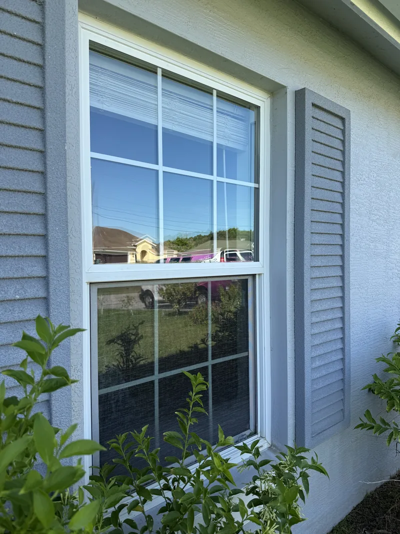 White colonial-grid window with a new low-E insulated impact glass unit installed in the original frame